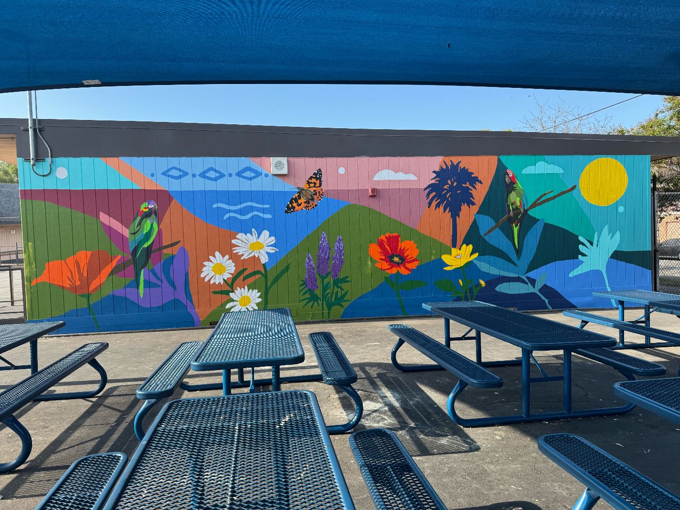 New mural with birds, flowers, and a California coastline in the school yard